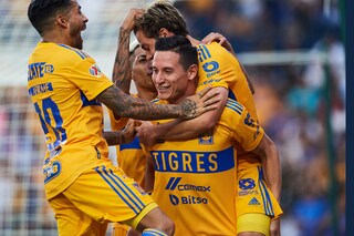 Four professional soccer players embrace after a victory.